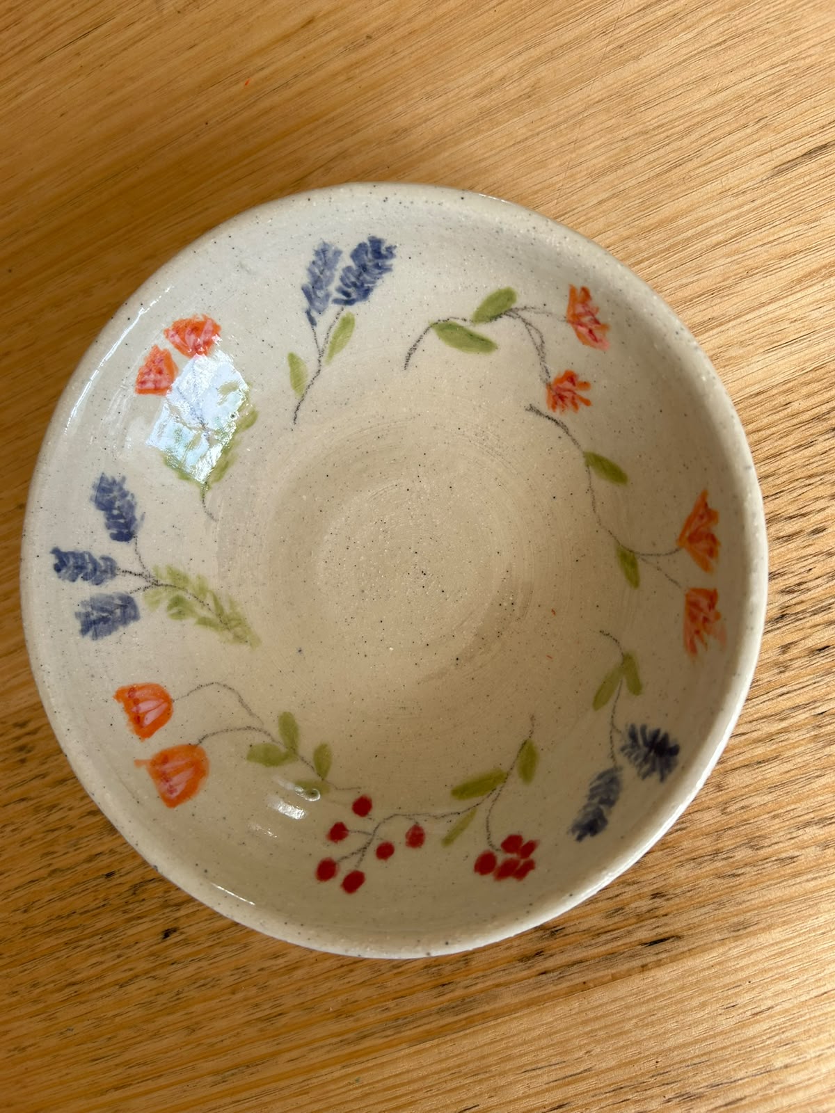 Ceramic bowl with a wreath of blue and orange flowers and red berries